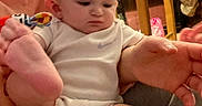 Michael is registered to the contest to win money with this photo: adult, baby, blanket, bottle, casual, clothing, curious, expression, face, foot, furniture, hand, holding, home, indoor, infant, onesie, person, table, toy