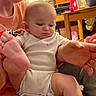Michael is registered to the contest to win money with this photo: baby, infant, person, indoor, adult, clothing, onesie, hand, foot, table, furniture, bottle, toy, blanket, face, expression, holding, home, casual, curious
