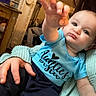 Michael joined the competition — help win amazing prizes! baby, child, person, hand, face, clothing, blue_shirt, sitting, indoor, adult_hand, knitted_sweater, curious, reaching, closeup, portrait, cozy, warm_lighting, home, expression, infant