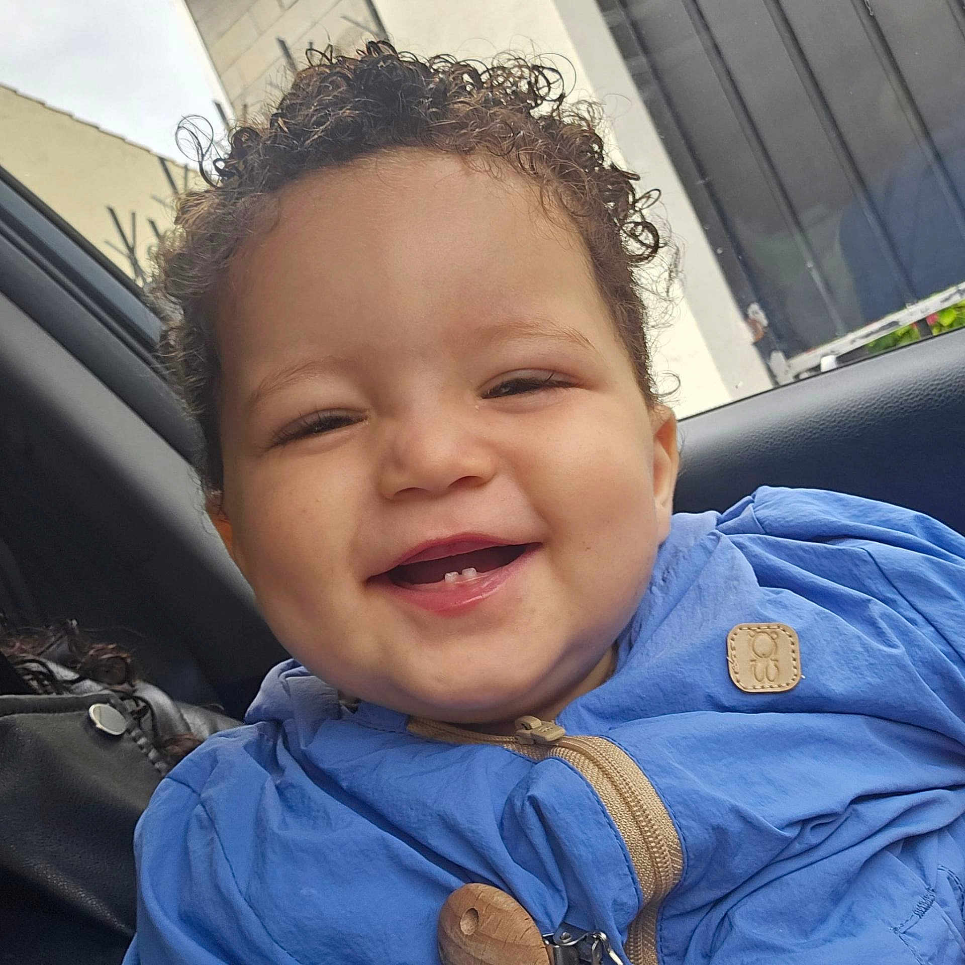Isaïa a rejoint le concours — aidez-le/la à gagner de superbes lots ! toddler, child, smiling, curly_hair, blue_jacket, teeth, face, portrait, happy, car_interior, seat, clothing, person, young_child, cute, baby, cheerful, closeup, indoor, casual
