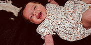 Oakley is registered to the contest to win money with this photo: baby, child, smile, happy, dress, floral, infant, lying_down, drool, skin, arm, face, person, cute, small, pattern, black, white, background, joyful