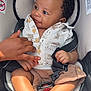 baby, child, car_seat, smiling, holding_hand, clothing, buttoned_shirt, shorts, safety_harness, infant, cute, happy, portrait, seated, skin, hand, foot, indoor, person, closeup