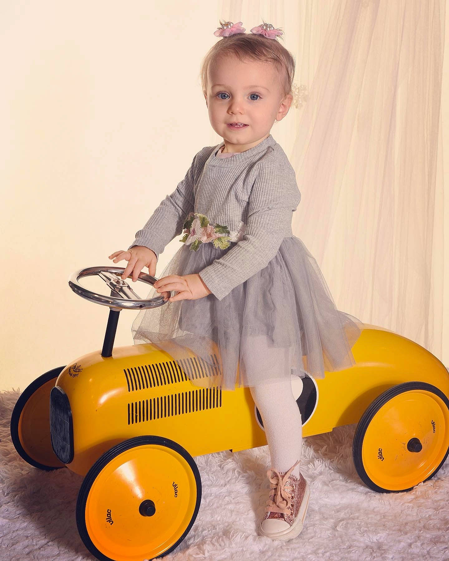 Tessa participe au concours pour gagner de l'argent avec cette photo : arm, automotive_design, automotive_tire, automotive_wheel_system, baby_toddler_clothing, curtain, happy, joy, motor_vehicle, person, product, riding_toy, rim, rolling, sleeve, smile, tire, toddler, toy, tread