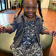 Iyumi is registered to the contest to win money with this photo: child, girl, smile, braids, pigtails, dress, jacket, sitting, waiting_room, wood_floor, bench, door, mural, earrings, portrait, happy, playful, indoor, person, candid
