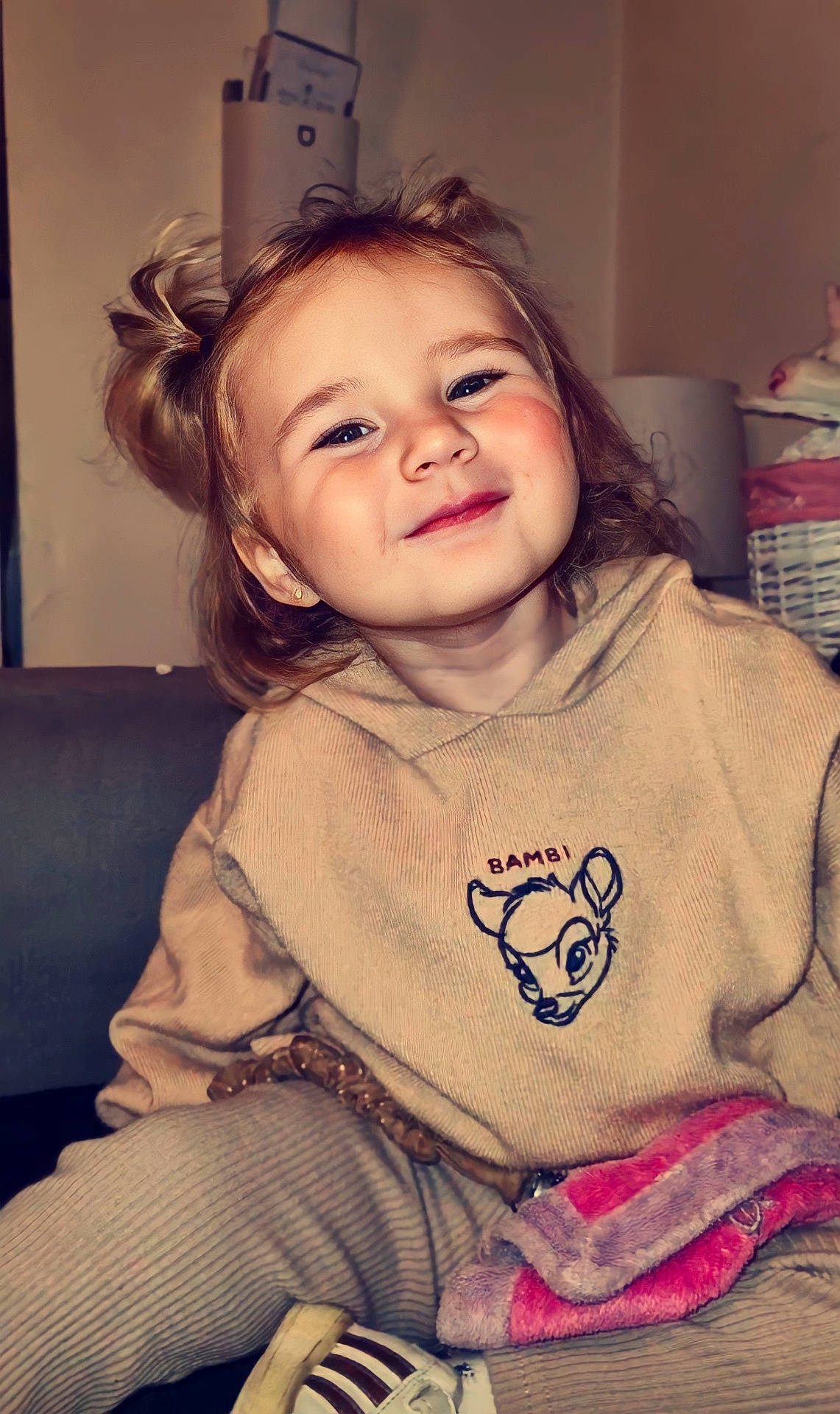 Yaëlie participe au concours pour gagner de l&#x27;argent avec cette photo : blanket, blonde_hair, casual, child, clothing, cozy, cute, face, furniture, happy, hoodie, indoor, person, pigtails, portrait, seated, smile, toddler, warm_lighting, youth