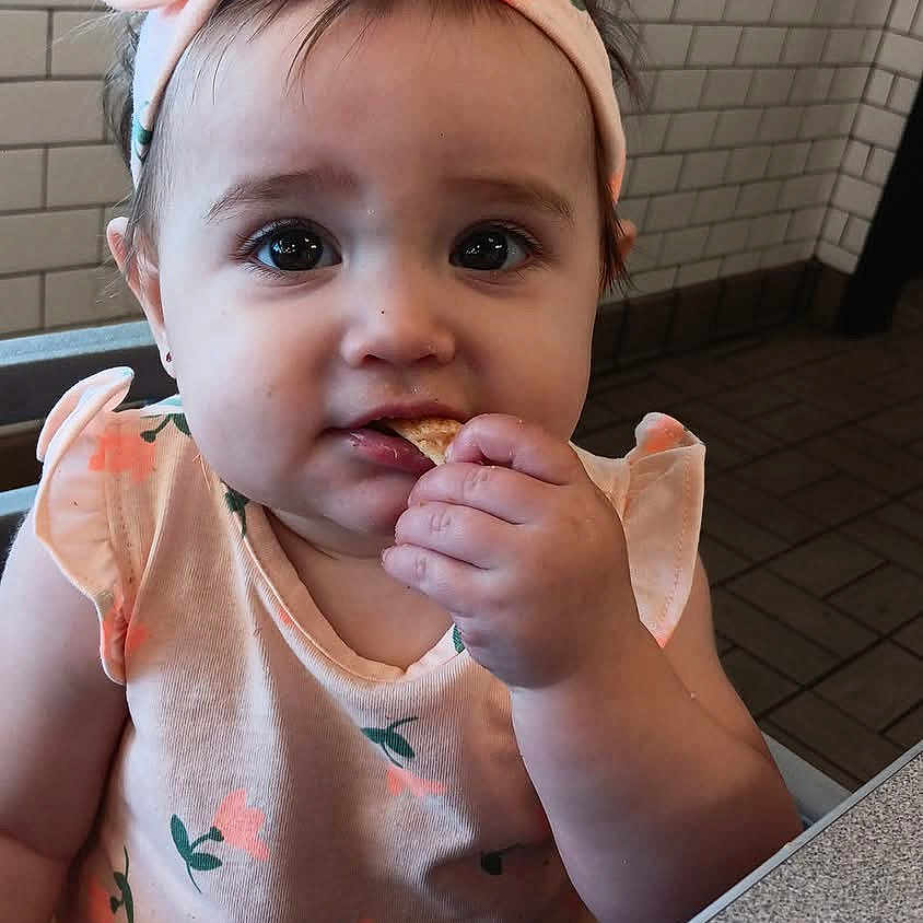 Amelia is registered to the contest to win money with this photo: baby, biting, bread, eating, face, food, head, person