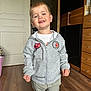 cabinet, casual, child, clothing, cute, door, face, floor, happy, home, hoodie, indoor, light, pants, person, smiling, standing, toddler, wooden_floor, young_child