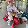William participe au concours pour gagner de l'argent avec cette photo : blue_car, cap, child, concrete_floor, furniture, glass, happy, indoor, outdoor, paw_patrol, pedal_car, play, red_car, reflection, shorts, sneakers, steering_wheel, toddler, toy, white_tshirt