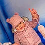 Yliana a rejoint le concours — aidez-le/la à gagner de superbes lots ! blue_wall, casual, child, childhood, cold_weather, cute, face, fun, gesture, hand_holding, outdoor, person, pink_hat, playful, pom_poms, seated, smiling, toddler, warm_clothing, winter_jacket