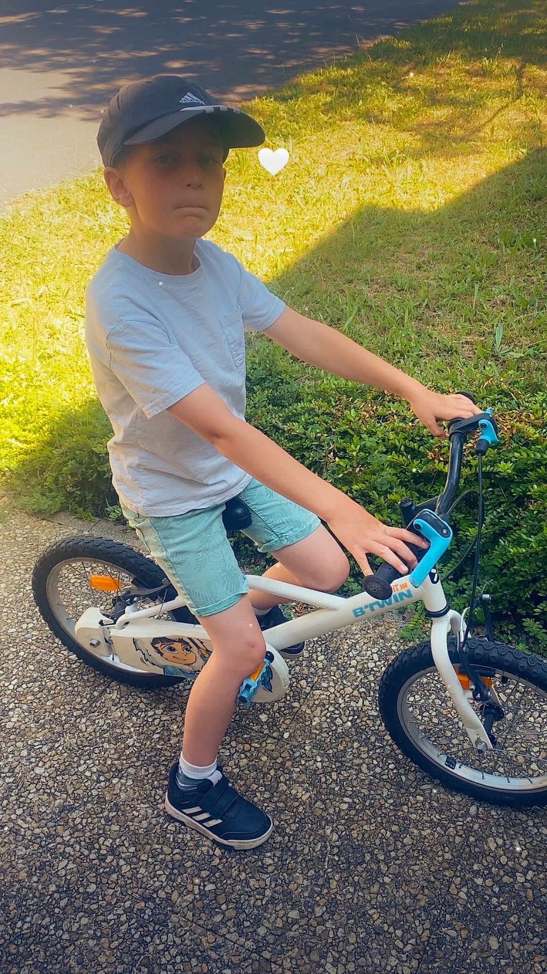 Liam a rejoint le concours — aidez-le/la à gagner de superbes lots ! child, boy, bicycle, bike, outdoor, grass, path, cap, shorts, tshirt, shoes, sunlight, shadow, greenery, playing, summer, casual_clothing, young, helmet_absent, exercise