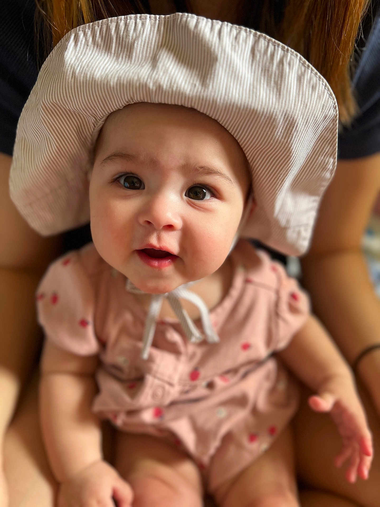 Eden is registered to the contest to win money with this photo: baby, child, hat, pink_outfit, person, portrait, cute, infant, face, eyes, skin, hand, sitting, apparel, headwear, indoor, young_child, smiling, closeup, human