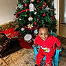 Marion is registered to the contest to win money with this photo: child, toddler, christmas_tree, christmas_ornaments, red_clothing, smiling, indoor, holiday, decorations, chair, carpet, gifts, toys, drums, braided_hair, festive, happy, home, seasonal, celebration