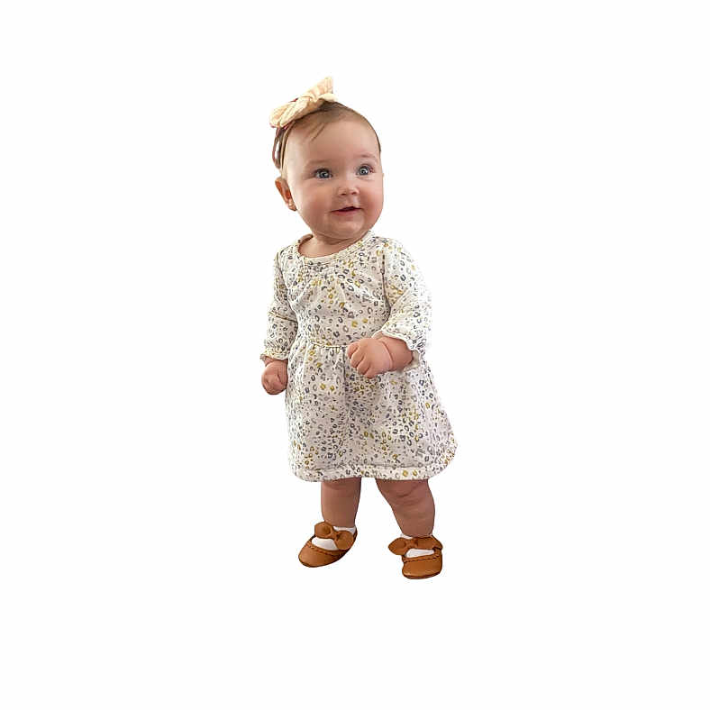 Emma is registered to the contest to win money with this photo: baby, clothing, coat, dress, face, fashion, footwear, formalwear, happy, head, longsleeve, person, photography, portrait, robe, sandal, shoe, sleeve, smile, standing