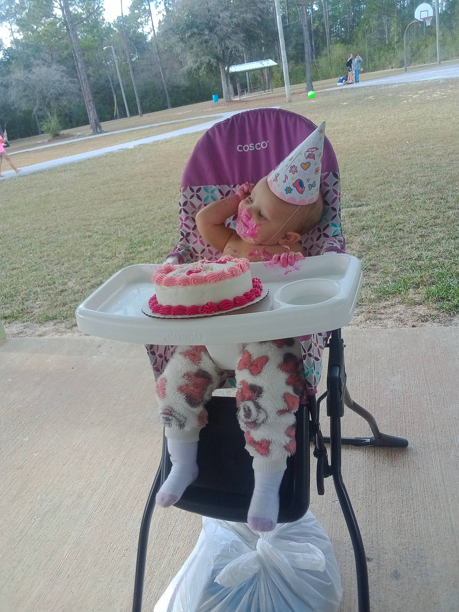Sharlene is registered to the contest to win money with this photo: baby_products, child, costume, event, fashion_accessory, fun, grass, hat, helmet, leisure, magenta, party_supply, person, pink, plant, recreation, sitting, sun_hat, table, toddler