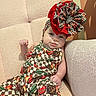 Harper-Mae joined the competition — help win amazing prizes! baby, infant, child, portrait, sitting, chair, indoor, fashion, bow, headband, colorful_clothing, patterned_outfit, red, checkered, fruit_pattern, plush_furniture, face, blue_eyes, raised_fist, smiling