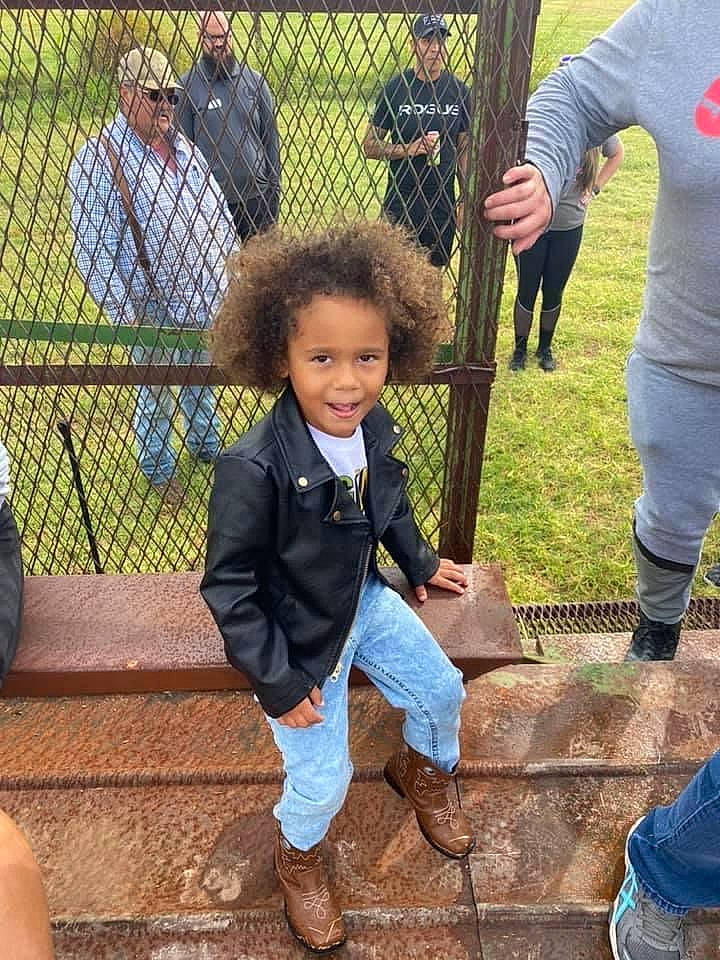 Xyler is registered to the contest to win money with this photo: boot, child, city, clothing, event, fence, fun, grass, leisure, people_in_nature, person, plant, play, public_space, recreation, shoe, smile, sneakers, soil, toddler