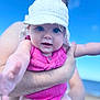adult, arm, baby, beach, blue_sky, child, closeup, hand, happy, hat, infant, outdoor, person, pink_clothing, portrait, sky, smiling, summer, sun_hat, vacation