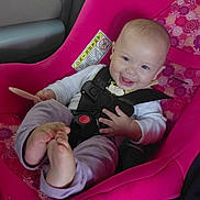 Marianna is registered to the contest to win money with this photo: baby, car_seat, child, smiling, happy, infant, seatbelt, pink, clothing, foot, hand, safety, vehicle_interior, cute, portrait, seat, person, young_child, toddler, bright_colors