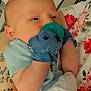 Callum is registered to the contest to win money with this photo: baby, pacifier, mittens, infant, arm, tattoo, floral_pattern, fabric, clothing, person, closeup, comfort, newborn, holding, skin, cute, resting, indoor, soft, blanket