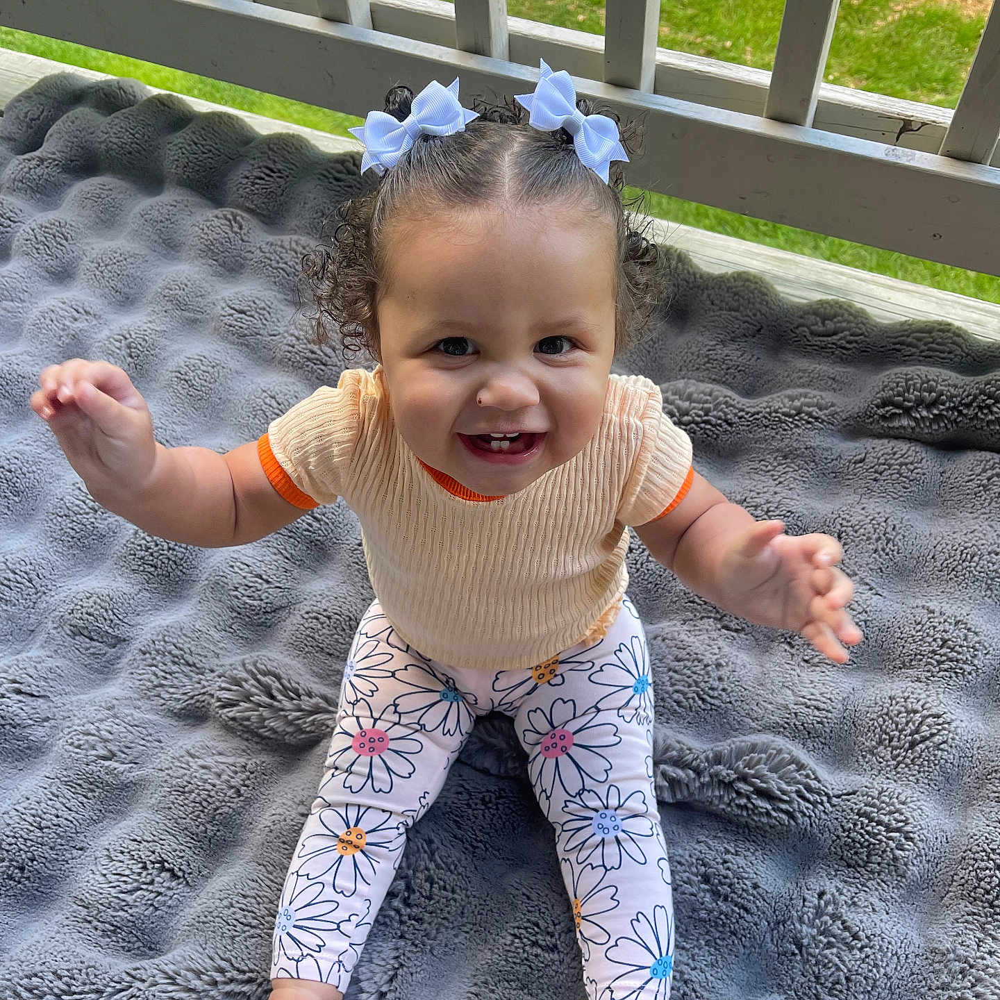 Mileigh joined the competition — help win amazing prizes! baby, blanket, child, clothing, curly_hair, cute, floral_pattern, grass, gray_blanket, hair_bows, happy, infant, leggings, outdoor, person, porch, railing, sitting, smiling, toddler