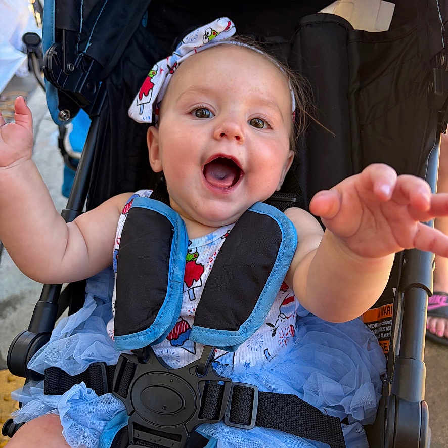 Oaklynn joined the competition — help win amazing prizes! baby, child, infant, smiling, happy, portrait, stroller, sitting, outdoor, blue_tutu, dress, bow, headband, harness, safety_belt, reaching, open_mouth, playful, sunlight, photography