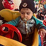 Enzo participe au concours pour gagner de l'argent avec cette photo : toddler, child, pacifier, beanie, mickey_mouse, kiddie_ride, steering_wheel, amusement_park, crowd, colorful, toy_car, red_steering_wheel, yellow_car, blue_car, casual_clothing, indoor, playful, young_child, focused, family_fun
