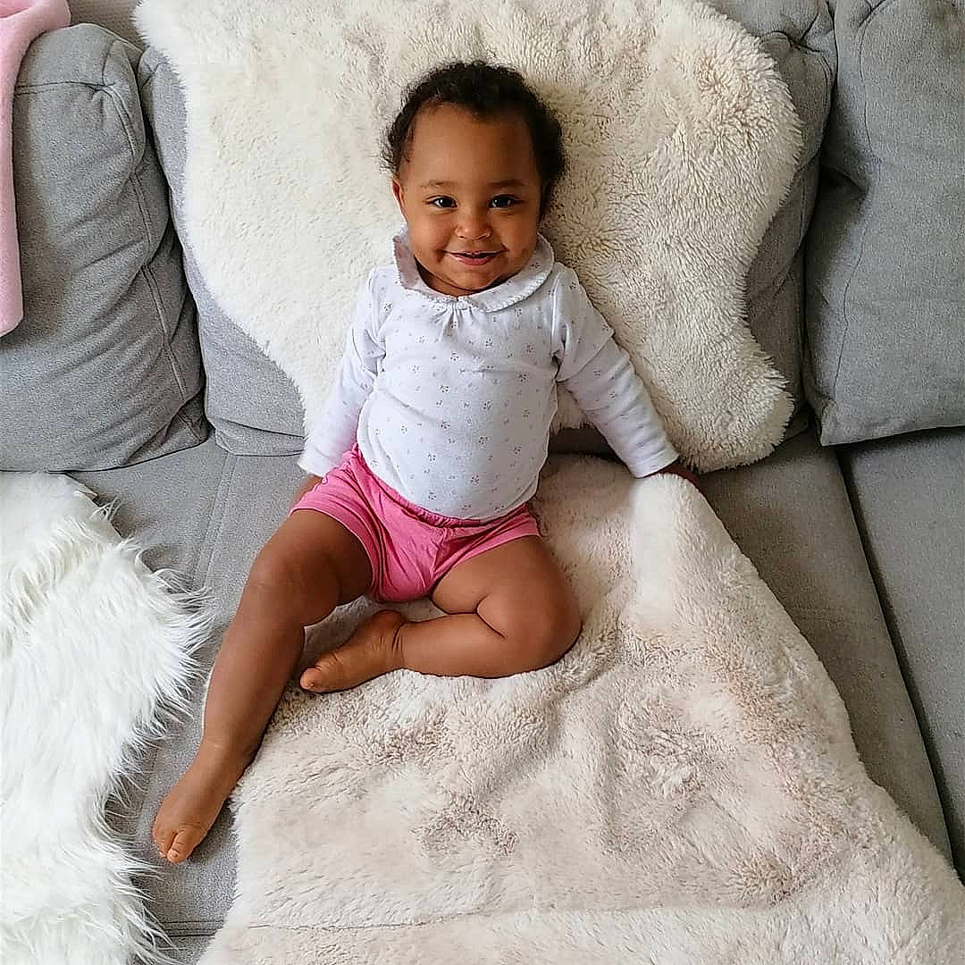 Sya participe au concours pour gagner de l'argent avec cette photo : abdomen, ankle, baby, baby_toddler_clothing, barefoot, child, comfort, eye, finger, foot, joy, linens, living_room, mouth, person, pink, sitting, sock, stomach, textile