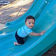 Bishop joined the competition — help win amazing prizes! baby, child, toddler, playground, slide, outdoor, park, climbing, sitting, blue_slide, striped_shirt, black_pants, curly_hair, face, portrait, looking_at_camera, playground_equipment, wood_chips, daylight, smiling