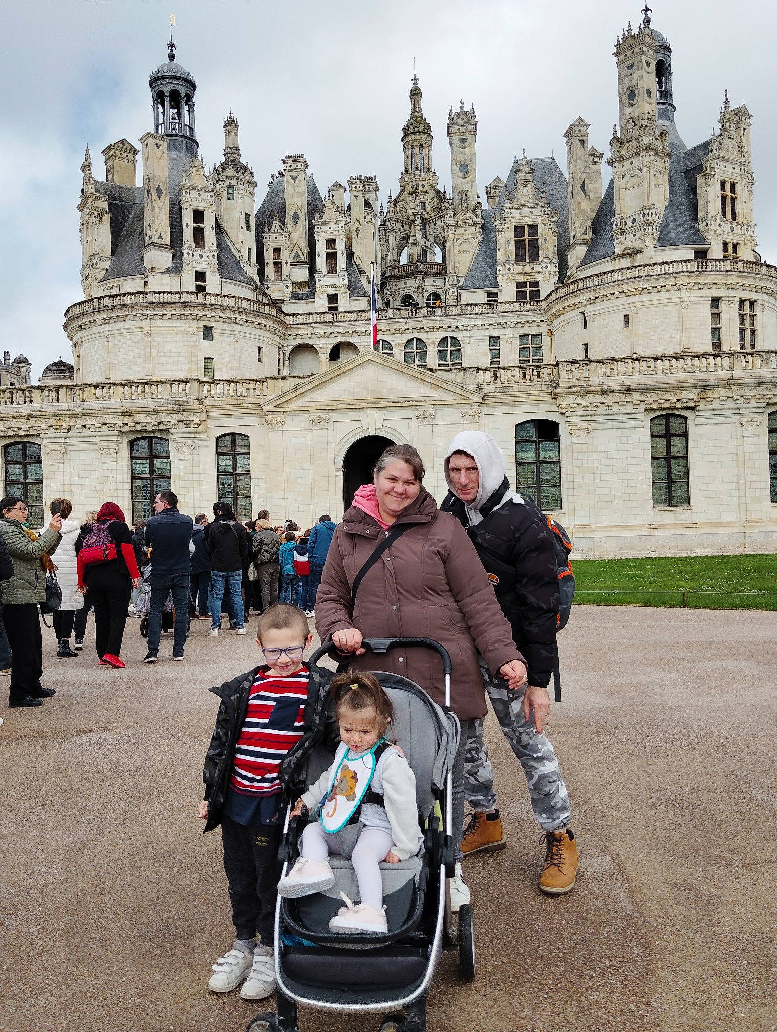 Nicole a rejoint le concours — aidez-le/la à gagner de superbes lots ! arch, baby_carriage, baby_products, building, castle, city, facade, fun, headwear, historic_site, jacket, joy, leisure, medieval_architecture, pedestrian, person, public_space, recreation, sky, street