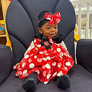 Mckayla is registered to the contest to win money with this photo: toddler, child, dress, polka_dot, red, black, headband, bow, mouse_ears, smile, chair, indoor, furniture, baby, cute, person, happy, seated, clothing, portrait