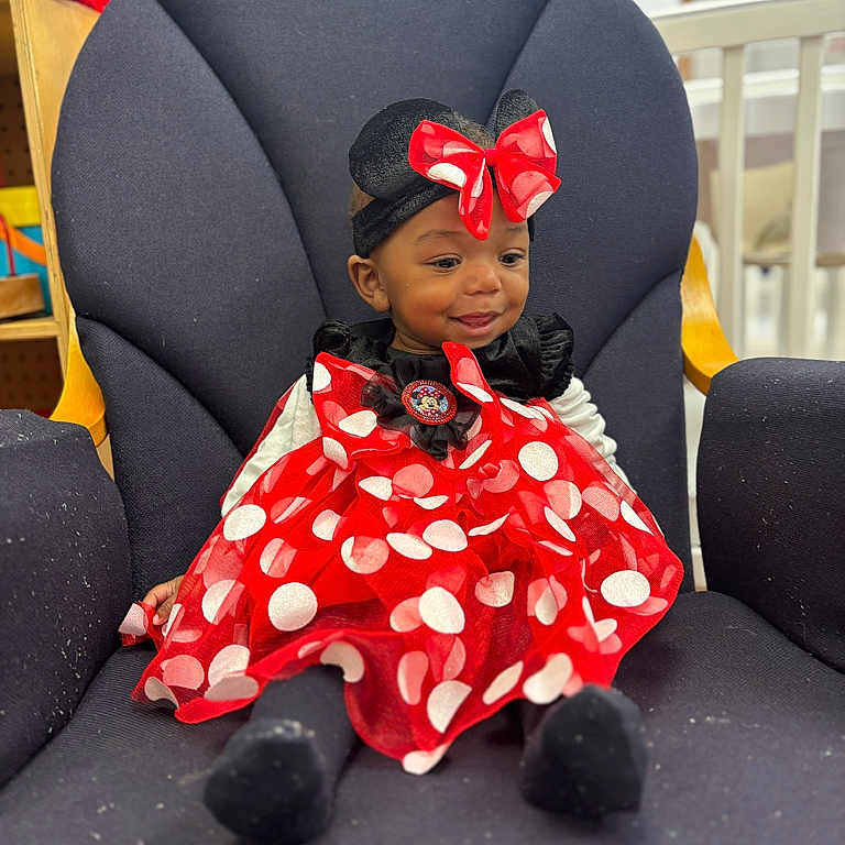 Mckayla is registered to the contest to win money with this photo: baby, black, bow, chair, child, clothing, cute, dress, furniture, happy, headband, indoor, mouse_ears, person, polka_dot, portrait, red, seated, smile, toddler