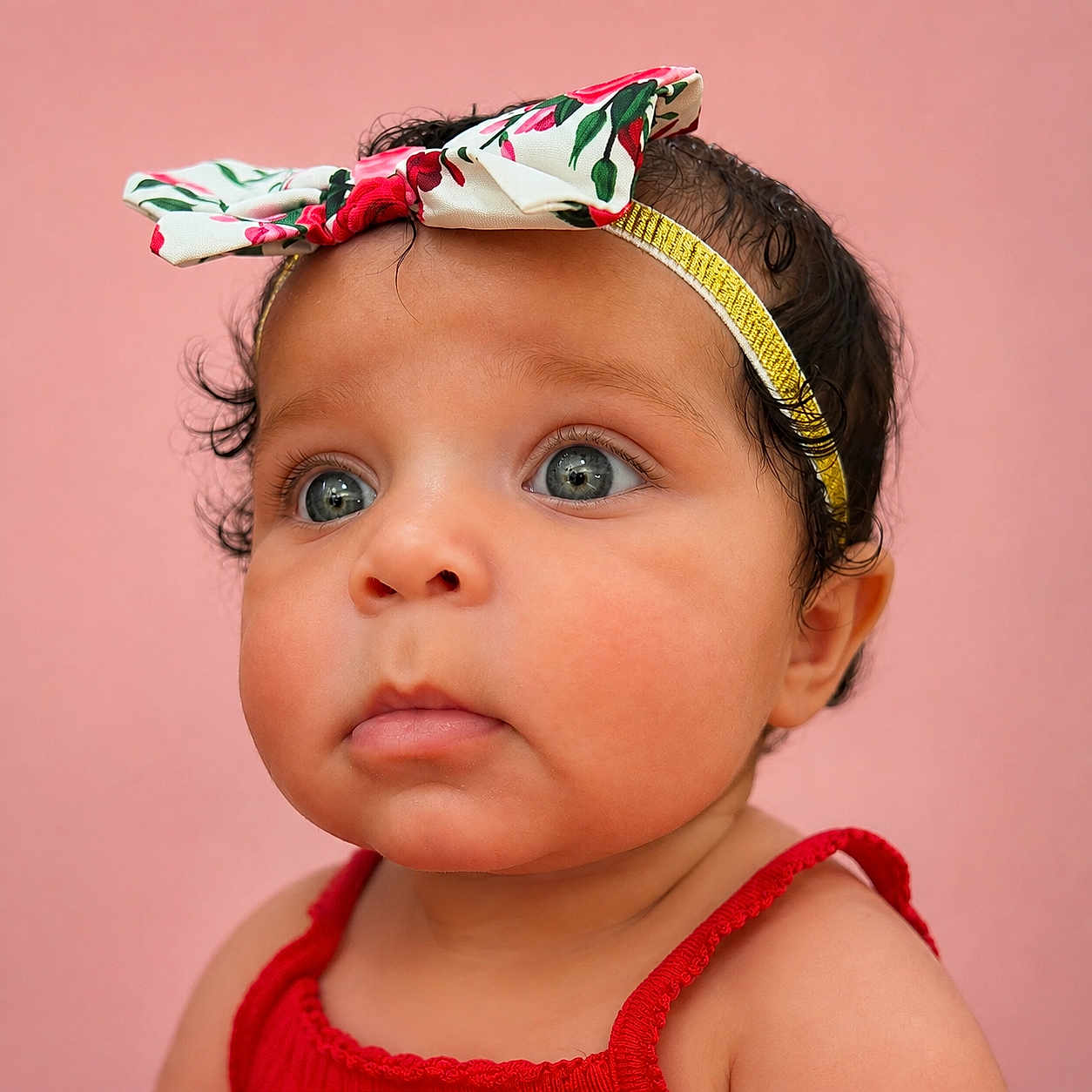 Ma Lani is registered to the contest to win money with this photo: baby, child, portrait, close_up, headband, red_clothing, curly_hair, blue_eyes, cute, infant, pink_background, face, skin, expression, looking_away, indoors, people, young_child, fashion, adorable