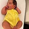 baby, infant, sleeping, yellow_onesie, cute, child, newborn, peaceful, hand, foot, face, curly_hair, skin, lying_down, soft_texture, blanket, indoors, portrait, adorable, resting