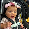 baby, infant, car_seat, pink_headband, pink_clothing, safety_harness, pacifier, child, cute, expression, face, hand, seat, straps, indoor, person, closeup, adorable, newborn, happy