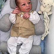 Robin a rejoint le concours — aidez-le/la à gagner de superbes lots ! baby, newborn, infant, vest, bow_tie, white_pajamas, socks, plush_toy, lamb, gray_cushion, baby_seat, face, hands, feet, soft_toy, indoor, portrait, cute, child, resting