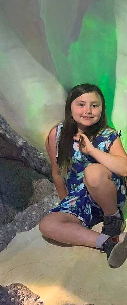 Nora is registered to the contest to win money with this photo: black_hair, cool, face, facial_expression, flash_photography, fun, grass, hair, happy, human_leg, jewellery, joy, leisure, long_hair, nature, person, sitting, skin, smile, t_shirt