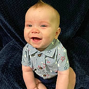Jensen is registered to the contest to win money with this photo: baby, blanket, blue, child, clothing, cute, expression, face, hands, happy, indoors, infant, person, portrait, shirt, sitting, skin, smiling, stars, young
