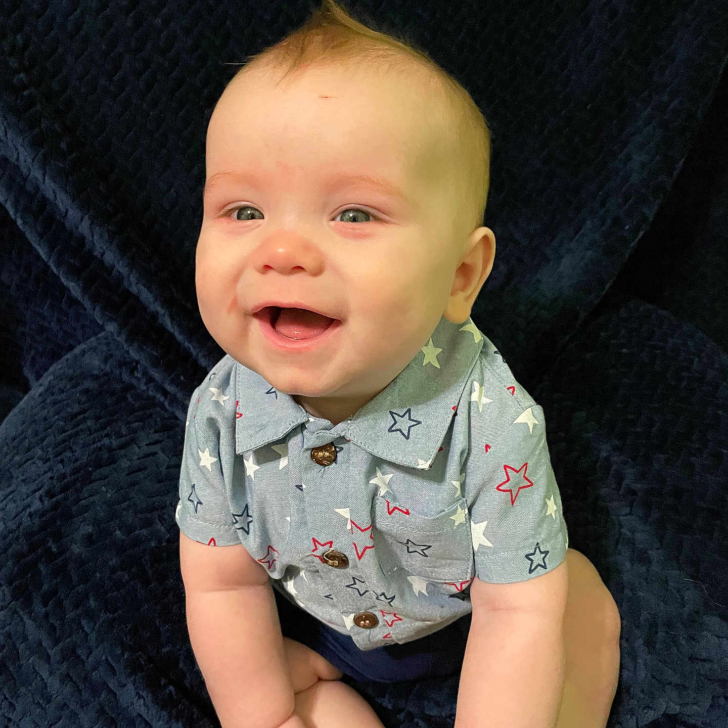 Jensen is registered to the contest to win money with this photo: baby, blanket, blue, child, clothing, cute, expression, face, hands, happy, indoors, infant, person, portrait, shirt, sitting, skin, smiling, stars, young