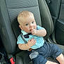 baby, child, infant, car_seat, blue_shirt, bow_tie, suspenders, thumb_sucking, cute, chubby_cheeks, car_interior, seatbelt, shorts, barefoot, portrait, person, young_child, sitting, light_skin, curious