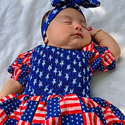 Rachel joined the competition — help win amazing prizes! baby, sleeping, headband, bow, dress, stars, stripes, red, white, blue, outdoor, blanket, child, peaceful, infant, portrait, clothing, pattern, resting, cute