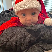 Kinsley joined the competition — help win amazing prizes! baby, child, santa_hat, red_clothing, blanket, bedroom, indoor, curious, face, wide_eyes, soft_texture, pillow, holiday, christmas, infant, person, cute, portrait, cozy, resting