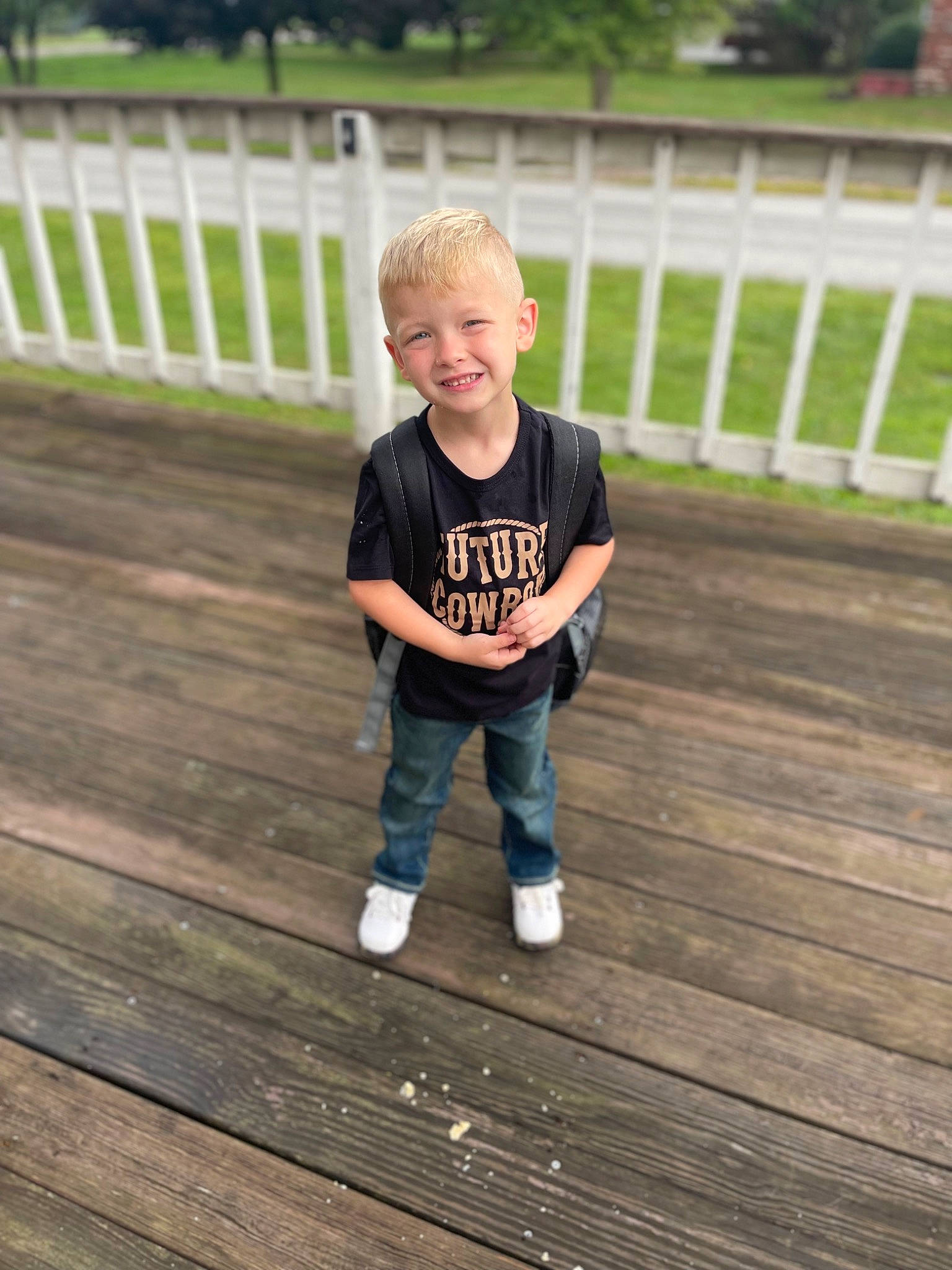 Daniel is registered to the contest to win money with this photo: child, denim, fence, flooring, fun, grass, hair, happy, hardwood, jeans, joy, leisure, person, recreation, shorts, sleeve, smile, t_shirt, toddler, tree