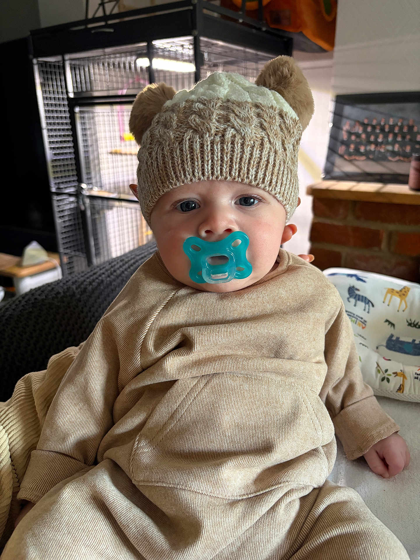 Lawson joined the competition — help win amazing prizes! baby, child, pacifier, hat, knitted_hat, beige_clothing, indoor, portrait, cute, infant, face, sitting, cozy, warm_clothing, headwear, young_child, person, furniture, blanket, comfort
