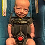 baby, car_seat, smile, infant, safety_harness, blue_fabric, warning_label, child, cute, young, seatbelt, indoor, portrait, infant_clothing, baby_face, small_person, happy, secure, close_up, human