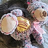 cat, stuffed_toy, bed, striped_bedspread, gray_cat, plush_toy, teddy_bear, pink_ribbon, golden_heart, cozy, indoor, pet, animal, feline, soft_texture, cute, relaxed, cuddling, toy, sleepy