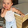 Lyana participe au concours pour gagner de l'argent avec cette photo : barefoot, carpet, child, cute, face, floor, furniture, happy, home, indoor, living_room, necklace, person, shorts, skin, smiling, standing, tank_top, toddler, wooden_table