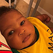 Ja'Majesty joined the competition — help win amazing prizes! arm, baby, bib, casual, closeup, clothing, comfort, expression, face, floor, furniture, head, indoors, infant, lying, person, portrait, skin, yellow, young