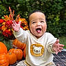 baby, child, infant, smiling, happy, outdoor, portrait, autumn, pumpkins, flowers, greenery, garden, sitting, hands_raised, tiger_shirt, striped_pants, plaid_blanket, curly_hair, seasonal_decor, close_up