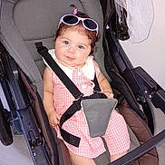 Candice participe au concours pour gagner de l'argent avec cette photo : baby, child, stroller, pink_dress, sunglasses, blue_eyes, smile, face, seatbelt, indoor, floor, baby_hair, cute, infant, person, clothing, footwear, baby_seat, safety_harness, portrait