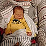 newborn, baby, sleeping, onesie, yellow_clothing, blanket, baby_carrier, patterned_fabric, cozy, infant, soft_toys, cushion, indoor, resting, cute, child, peaceful, wrapped, small_hands, head